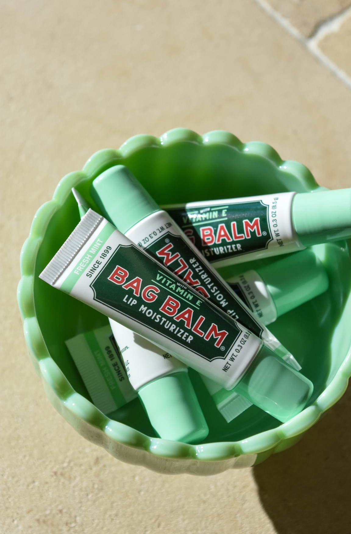Tubes of mint lip balm in green bowl