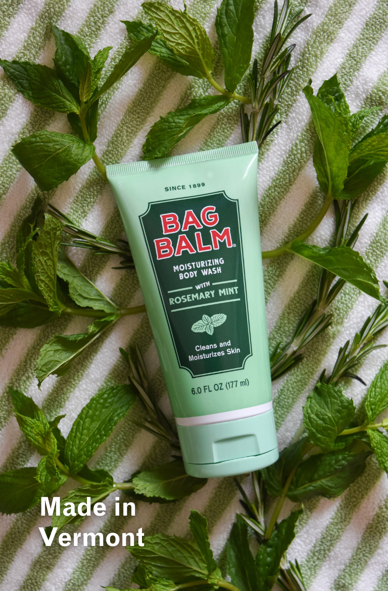 Body Wash Tube on striped towel with Rosemary + Mint Plants surrounding it