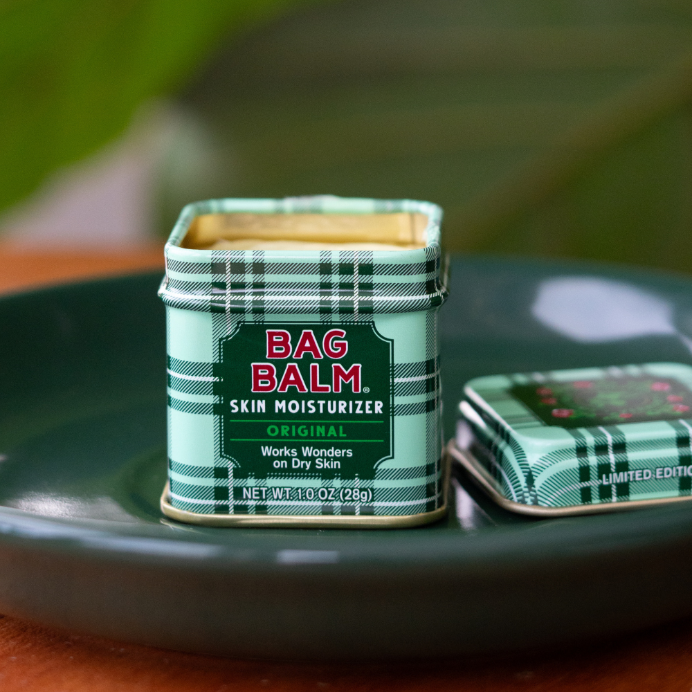 Bag Balm skin moisturizer tin with plaid design on a green surface
