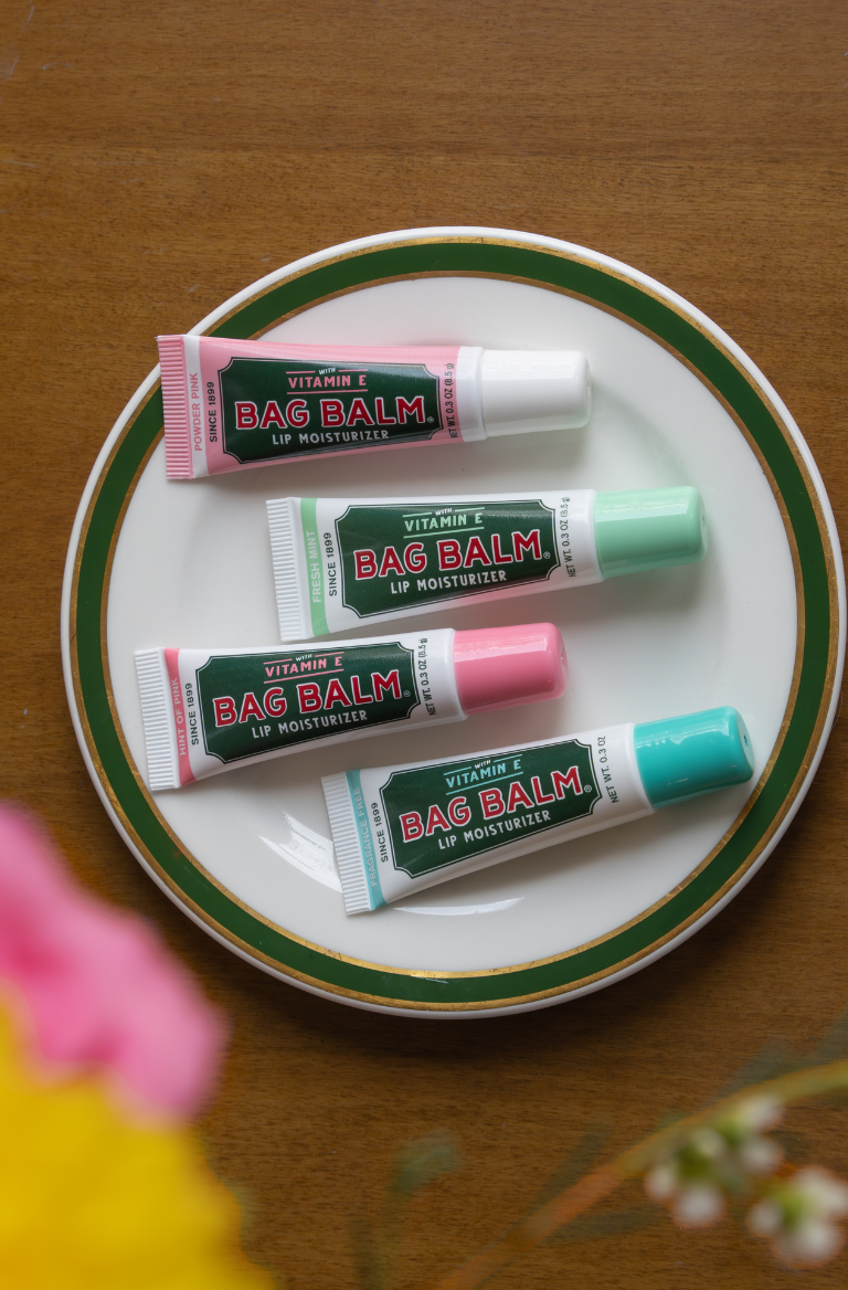 Four tubes of Bag Balm lip balm on a white plate with green rim.