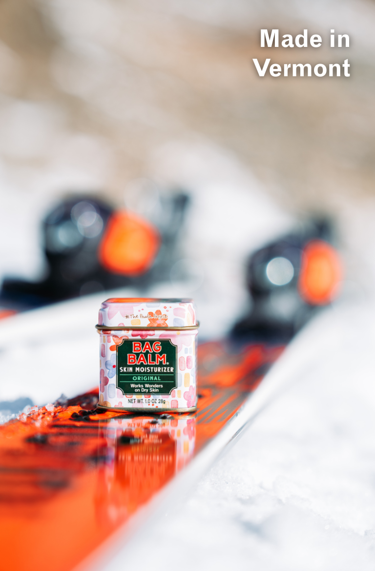 Paula Moltzan X Skida Print Bag Balm 1oz Tin on pair of skis in snow